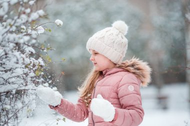 Parkta kar yağan mutlu küçük kız