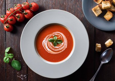 Eski beyaz ahşap arka planda taze fesleğen, kızarmış ekmek, kızarmış ekmek ve cron ile domates çorbası..