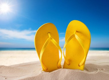 Kumsalda bir çift plaj terliği.