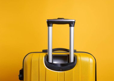 Sarı valiz ve sarı arka planda seyahat şapkası.