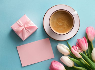 Kahve fincanı ve pembe arka planda laleler. Metin için boşluk olan üst görünüm.