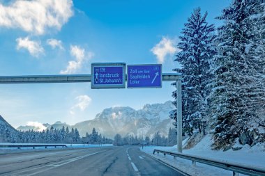 Avusturya Alplerinde kışın dağ yolu, Salzburg bölgesi, Innsbruck, Zell am See, Saalfelden, Lofer yol tabelası, karlı köknar ağacı