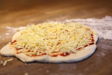 Ev yapımı pizza hamuru, mozarella peyniri ve domates sosu.