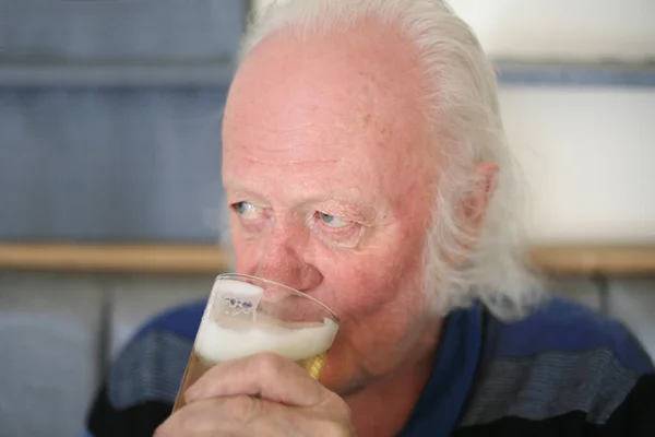 seventy year old senior old man drinking a pint of beer in a british pub in the uk