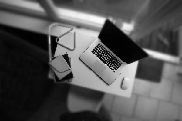 above view of a laptop computer and notebook on a desk shot in monochrome black and white in a modern home