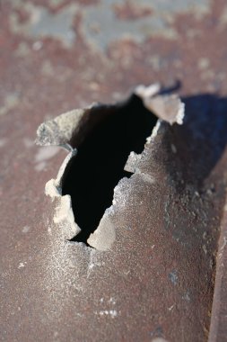 Hole in metal from a real missile explosion. After bombing. War in Ukraine, terror and genocide of Ukrainian people. Russian missile destroyed houses and metallic garages in residential area