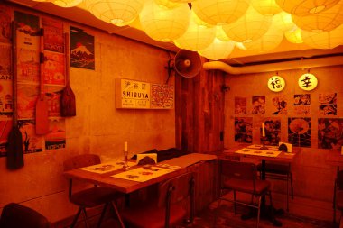 KYIV, UKRAINE, APRIL 21, 2022: Interior of Asian restaurant in centre of Kyiv city, capital of Ukraine. Japanese pictures and boat oars hang on the walls, yellow lanterns hanging from the ceiling