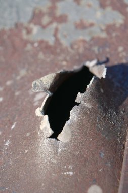Hole in metal from a real missile explosion. After bombing. War in Ukraine, terror and genocide of Ukrainian people. Russian missile destroyed houses and metallic garages in residential area