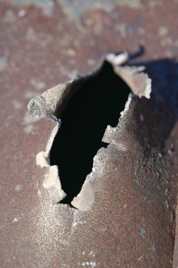Hole in metal from a real missile explosion. After bombing. War in Ukraine, terror and genocide of Ukrainian people. Russian missile destroyed houses and metallic garages in residential area