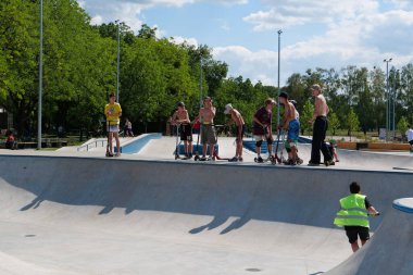 KYIV, UKRAINE, 26 Temmuz 2022: Kyiv şehrindeki çok amaçlı sergi kompleksi Ukrayna 'nın merkezindeki yeni açık hava spor sahasında erkekler scooter sürüyor