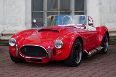 KYIV, UKRAINE, NOVEMBER 13, 2022: Red retro car stands at Expo Center. AC Cobra, sold in United States as Shelby Cobra and AC Shelby Cobra, is a sports car manufactured by British company AC Cars