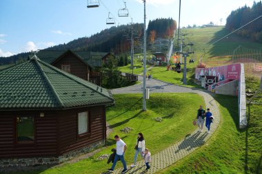 BUKOVEL, UKRAINE, OCTOBER 13, 2022: People on ski lift in Bukovel - beautiful village and largest ski resort in Carpathian Mountains, Ivano-Frankivsk Oblast, western Ukraine