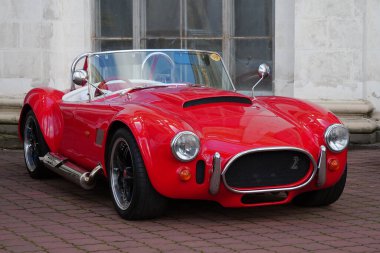 KYIV, UKRAINE, NOVEMBER 13, 2022: Red retro car stands at Expo Center. AC Cobra, sold in United States as Shelby Cobra and AC Shelby Cobra, is a sports car manufactured by British company AC Cars