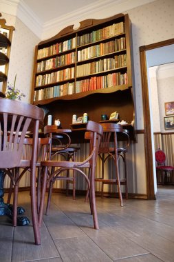 KOLOMYIA, UKRAINE, 20 AĞUSTOS: Masaları, sandalyeleri ve kitaplıkları olan kafenin içi