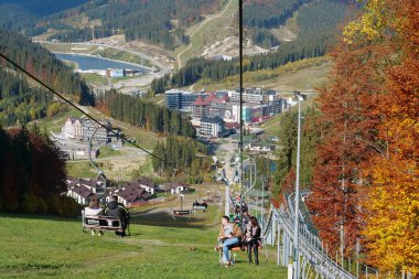 BUKOVEL, UKRAINE, OKTOBER 13 Ekim 2022: Bukovel 'de kayak asansöründeki insanlar - Karpat Dağları' ndaki güzel köy ve en büyük kayak merkezi, Ivano-Frankivsk Oblastı, batı Ukrayna