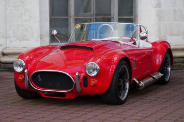 KYIV, UKRAINE, NOVEMBER 13, 2022: Red retro car stands at Expo Center. AC Cobra, sold in United States as Shelby Cobra and AC Shelby Cobra, is a sports car manufactured by British company AC Cars