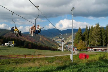 BUKOVEL, UKRAINE, OCTOBER 13, 2022: People on ski lift in Bukovel - beautiful village and largest ski resort in Carpathian Mountains, Ivano-Frankivsk Oblast, western Ukraine