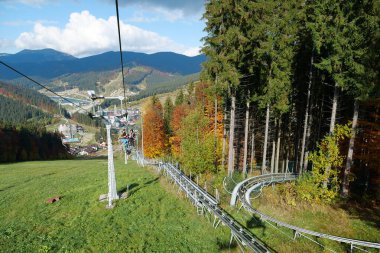 BUKOVEL, UKRAINE, OCTOBER 13, 2022: People on ski lift in Bukovel - beautiful village and largest ski resort in Carpathian Mountains, Ivano-Frankivsk Oblast, western Ukraine