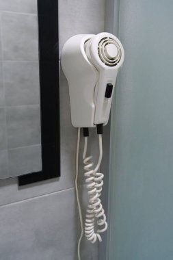 White hair dryer hanging on the wall in the bathroom