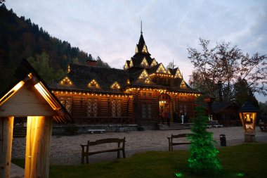 YAREMCHE, CARPATHIANS, UKRAINE, EKİM 16 Ekim 2022: Batı Ukrayna 'daki Yaremche şehrindeki ünlü Hutsulshyna restoranının yakınındaki insanlar. Hutsulshchyna restoranının ahşap binası, mimarlık abidesi.