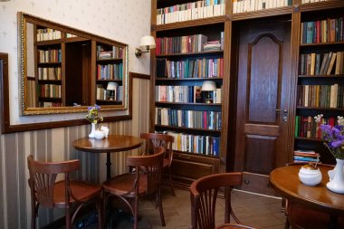 KOLOMYIA, UKRAINE, 20 AĞUSTOS: Masaları, sandalyeleri ve kitaplıkları olan kafenin içi
