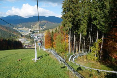 BUKOVEL, UKRAINE, OCTOBER 13, 2022: People on ski lift in Bukovel - beautiful village and largest ski resort in Carpathian Mountains, Ivano-Frankivsk Oblast, western Ukraine
