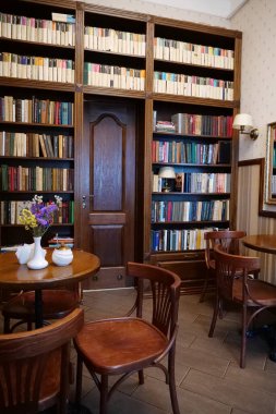 KOLOMYIA, UKRAINE, AUGUST 20, 2022: Interior of cafe with tables, chairs and bookcases clipart