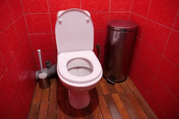 オープン蓋付きの白いトイレボウル 金属ゴミ入れ トイレブラシと赤い壁のタイルとトイレの部屋のインテリア — ストック写真