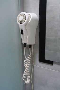 White hair dryer hanging on the wall in the bathroom