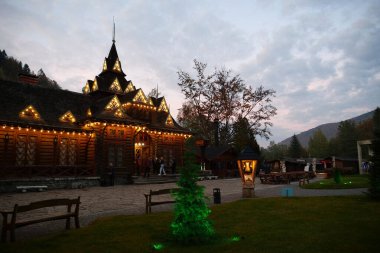 YAREMCHE, CARPATHIANS, UKRAINE, EKİM 16 Ekim 2022: Batı Ukrayna 'daki Yaremche şehrindeki ünlü Hutsulshyna restoranının yakınındaki insanlar. Hutsulshchyna restoranının ahşap binası, mimarlık abidesi.
