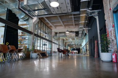 IVANO-FRANKIVSK, UKRAINE, AĞUSTOS 20, 2022: Eski fabrika atölyesinde birlikte çalışan insanlar. Ortak çalışma - birçok şirketin işçilerinin ofis alanını paylaştığı bir düzenleme