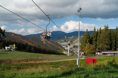 BUKOVEL, UKRAINE, OCTOBER 13, 2022: People on ski lift in Bukovel - beautiful village and largest ski resort in Carpathian Mountains, Ivano-Frankivsk Oblast, western Ukraine