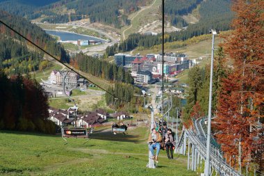 BUKOVEL, UKRAINE, OKTOBER 13 Ekim 2022: Bukovel 'de kayak asansöründeki insanlar - Karpat Dağları' ndaki güzel köy ve en büyük kayak merkezi, Ivano-Frankivsk Oblastı, batı Ukrayna