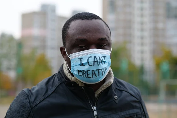 stock image African american man activist in medical mask with an inscription I CANT BREATHE looks at the camera. Black Lives Matter, BLM, racial discrimination, mass protests in USA