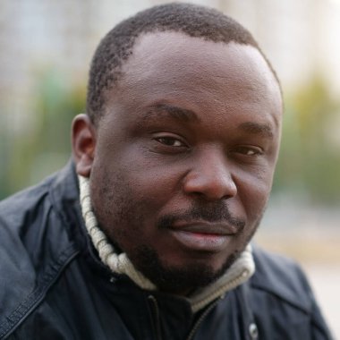 Nijeryalı Afrikalı Amerikalı adam kameraya bakıyor.