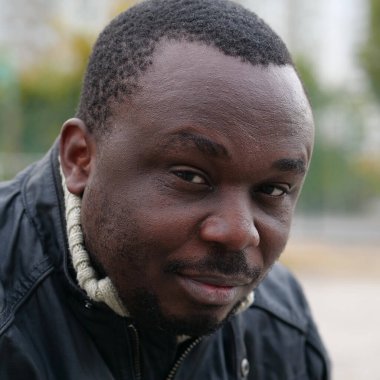 Nijeryalı Afrikalı Amerikalı adam kameraya bakıyor.