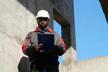 Afrikalı Amerikalı işçiler inşaat sahasında çalışma belgeleriyle duruyorlar.