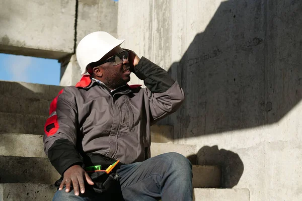 非裔美国人工人坐在建筑工地的楼梯上 他感到很不舒服 而且很头疼 — 图库照片