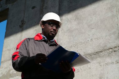 Afrikalı Amerikalı işçiler inşaat sahasında çalışma belgeleriyle duruyorlar.