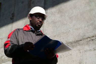 Afrikalı Amerikalı işçiler inşaat sahasında çalışma belgeleriyle duruyorlar.