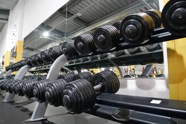 stock image KYIV, UKRAINE, JUNE 2, 2023: Set of dumbbells with different weights in the gym. Fit muscle body workout. Athletes workout in gym. Dumbbells for pumping the body