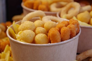 Kızarmış patates, kızarmış peynir topları ve büyük kağıt kaselerde diğer fırınlanmış yiyecekler.