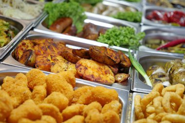 Fast food restoranında kaynatılmış, kızartılmış ve bol yağda kızartılmış çeşitli yemekler. Çeşitli şekillerde pişirilmiş patatesler. Patates kızartması, kızarmış patates, soğan, marul ve diğer sebzeler.