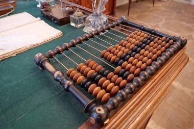 Old abacus, counting frame lies on the table in office. Close-up view highlights an antique wooden abacus with well-worn beads clipart