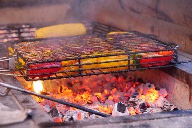 Biberler ızgarada sıcak kömürde pişirilir. Sarı ve kırmızı biberler barbeküde ızgara, kömür brazier