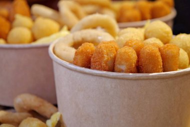 Kızarmış patates, kızarmış peynir topları ve büyük kağıt kaselerde diğer fırınlanmış yiyecekler.