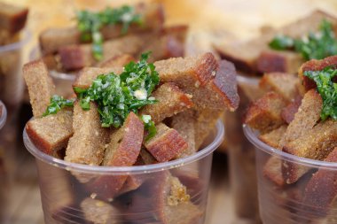 Kızarmış tuzlu ekmek, yeşil soğan, tereyağı ve sarımsak. Küçük kızarmış ekmek parçaları plastik bardaklarda.