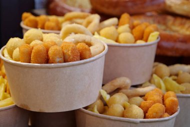 Kızarmış patates, kızarmış peynir topları ve büyük kağıt kaselerde diğer fırınlanmış yiyecekler.