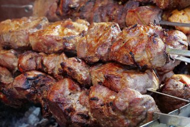 Barbeküde büyük şiş kebap. Yağlı, sağlıksız, kısmen yanmış kolesterollü et. Et, ızgarada sıcak kömürde pişirilir.