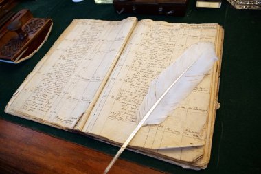 KYIV, UKRAINE, FEBRUARY 27, 2024: Old recipe book and a white feather pen for writing lies on table in old pharmacy in Kyiv, Ukraine clipart